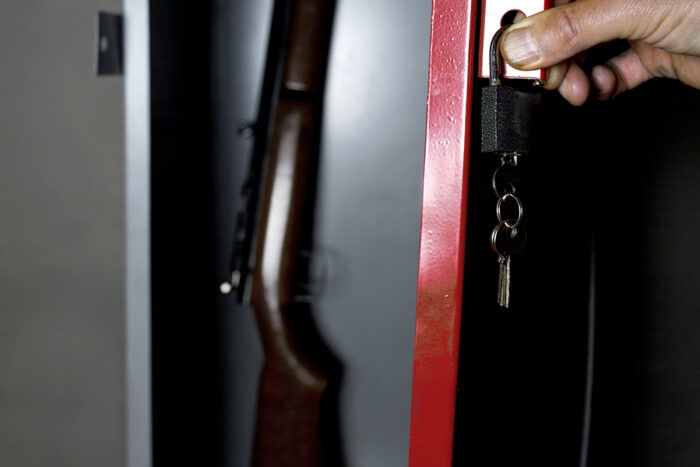 Human hand opening a metal safe with a gun inside, studio cropped shot